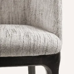 Fragment krzesła z tapicerowanym siedziskiem i oparciem w odcieniach szarości, z widoczną ciemną, drewnianą ramą i nogami.