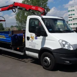 Samochód dostawczy z dźwigiem HDS firmy z Makowa Mazowieckiego, załadowany materiałami budowlanymi H+H. Widoczny logotyp firmy na drzwiach.