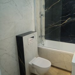 Oleksandr Kachkar GREENINDI - Nowoczesna łazienka z marmurowymi płytkami, wiszącą toaletą z czarnym panelem i kabiną prysznicową ze złotymi żyłami. Ukończona aranżacja wnętrza.