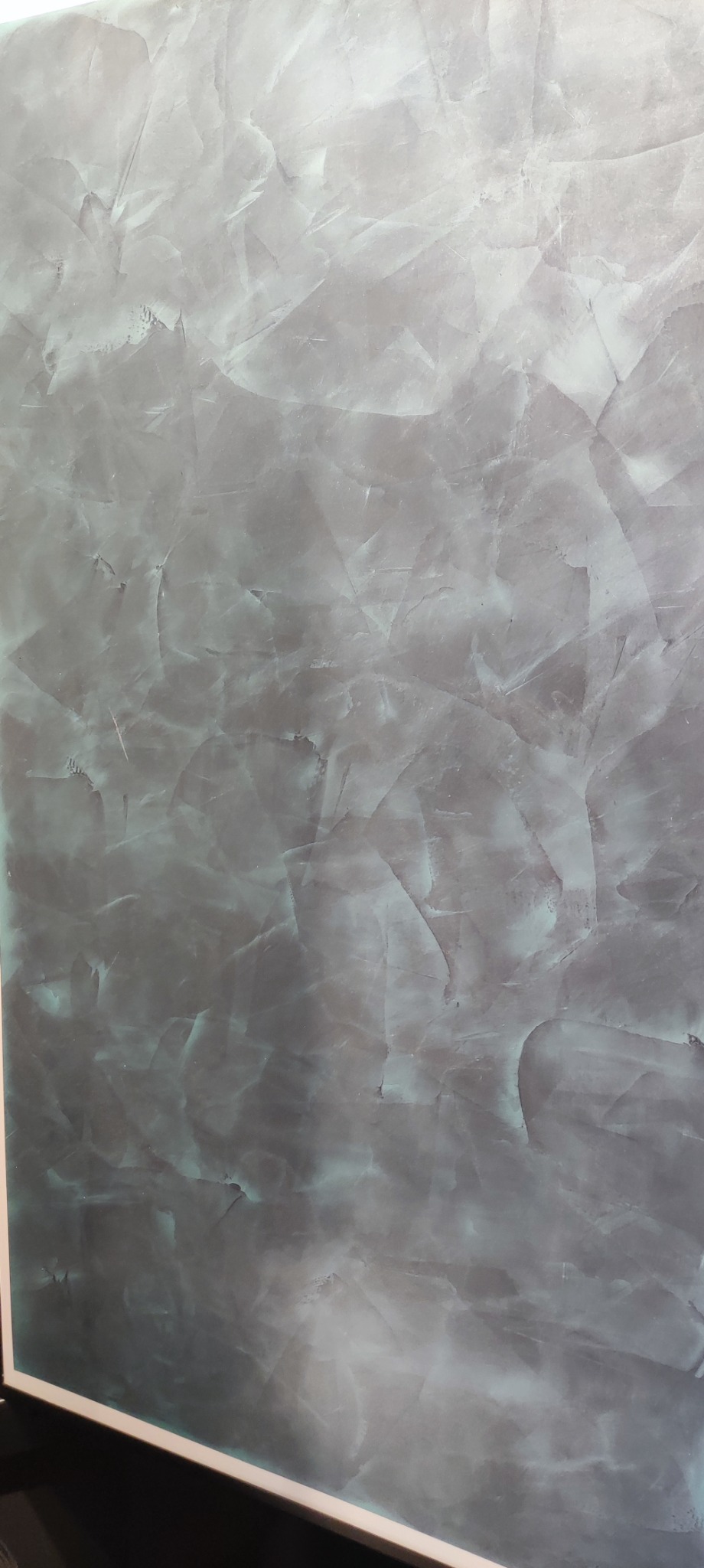 Dekoracyjna ściana w odcieniach szarości i błękitu z efektem marmuru, wykonana techniką stiuku weneckiego, prezentująca unikalny wzór i fakturę.