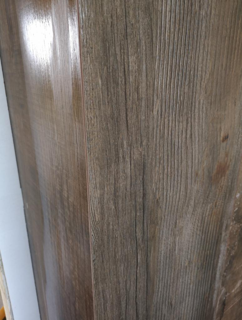 Ułożona pod kątem brązowa podłoga z paneli imitujących drewno w Stróży, widoczne delikatne refleksy światła na powierzchni.