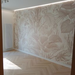 L.S Project - Jasne wnętrze z parkietem w jodełkę i tapetą w motywy dżungli z ukrytymi zwierzętami, oświetlenie LED podsufitowe, biały grzejnik.