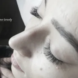 Profil twarzy kobiety po zabiegu przedłużania rzęs metodą objętościową, z widocznym logo salonu 'mc beauty' w lewym g&oacute;rnym rogu.