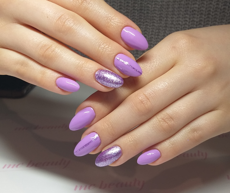 Dłonie z manicure hybrydowym w odcieniach fioletu i brokatu, jeden paznokieć zdobiony srebrną linią, na białym tle z delikatnym logo salonu.