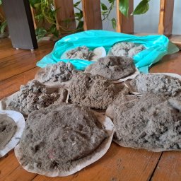 PHU MARTYNA-CZYSZCZENIE ŁÓŻEK,KANAP,NAROŻNIKÓW DYWANÓW I FOTELI KIRBY - Kłęby kurzu i brudu zebrane podczas sprzątania, ułożone na drewnianej podłodze obok worka. Widoczne drobinki i włókna. Zbliżenie na efekt czyszczenia.