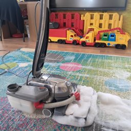 PHU MARTYNA-CZYSZCZENIE ŁÓŻEK,KANAP,NAROŻNIKÓW DYWANÓW I FOTELI KIRBY - Pranie dywanu odkurzaczem piorącym z widoczną pianą. W tle zabawki dziecka i meble. Usługa prania dywanów w domu klienta.