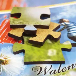 Niedopasowane elementy układanki z motywem walentynkowym, leżące na tle z nadrukiem, ukazującym postać skaczącej osoby, dmuchawca i czerwone serce.