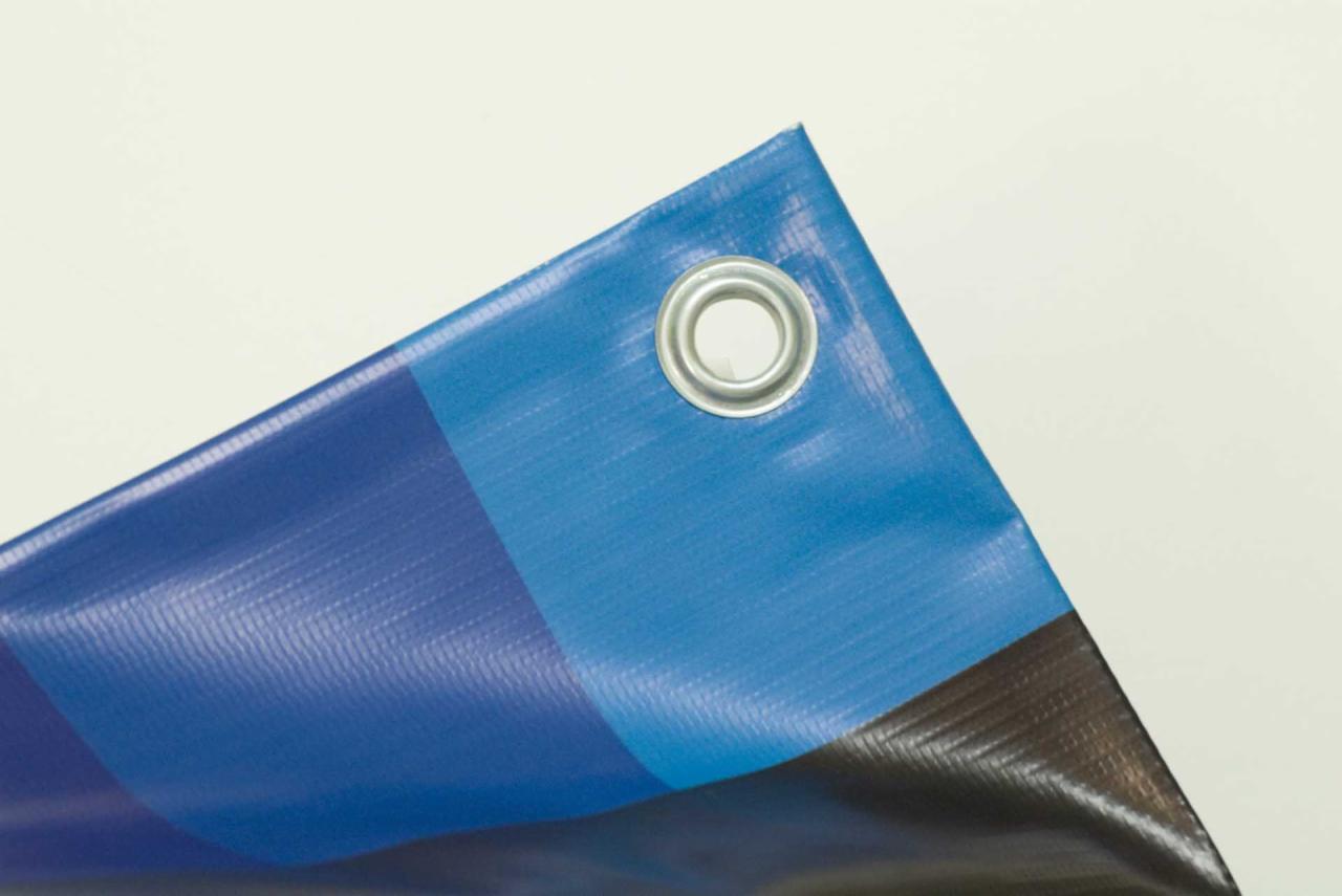 Fragment niebieskiego banera z metalowym oczkiem w rogu, widoczna struktura materiału i gradient kolorów.