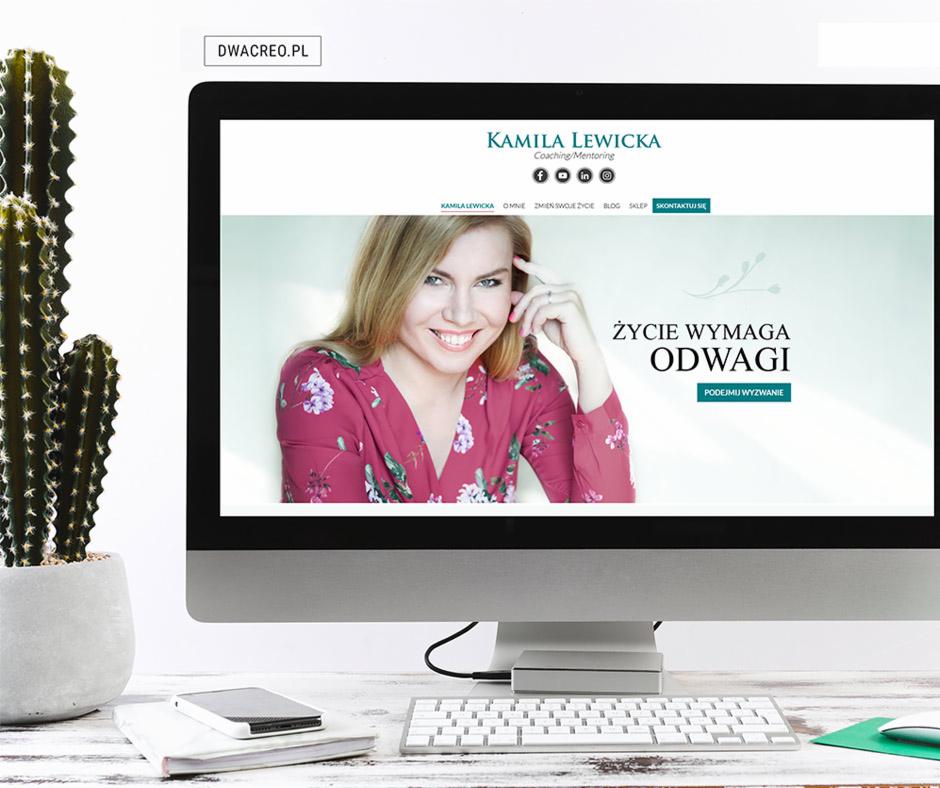 Monitor iMac wyświetlający stronę internetową z wizerunkiem kobiety, obok kaktus w doniczce, telefon na książce i klawiatura na biurku.