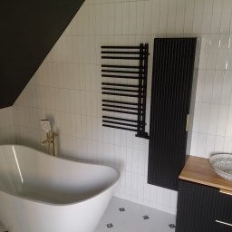 AnmarBud - Nowoczesna łazienka z wolnostojącą białą wanną, czarnymi grzejnikami drabinkowymi i umywalką nablatową w stylu boho, na tle białych, pionowo ułożonych płytek i czarnego skosu sufitu.