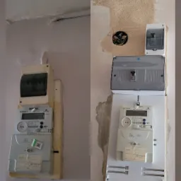 Porównanie stanu licznika elektrycznego przed i po wymianie: stary, pożółkły licznik po lewej, nowy, biały licznik z nową obudową i skrzynką bezpiecznikową po prawej stronie, widoczne ślady po...