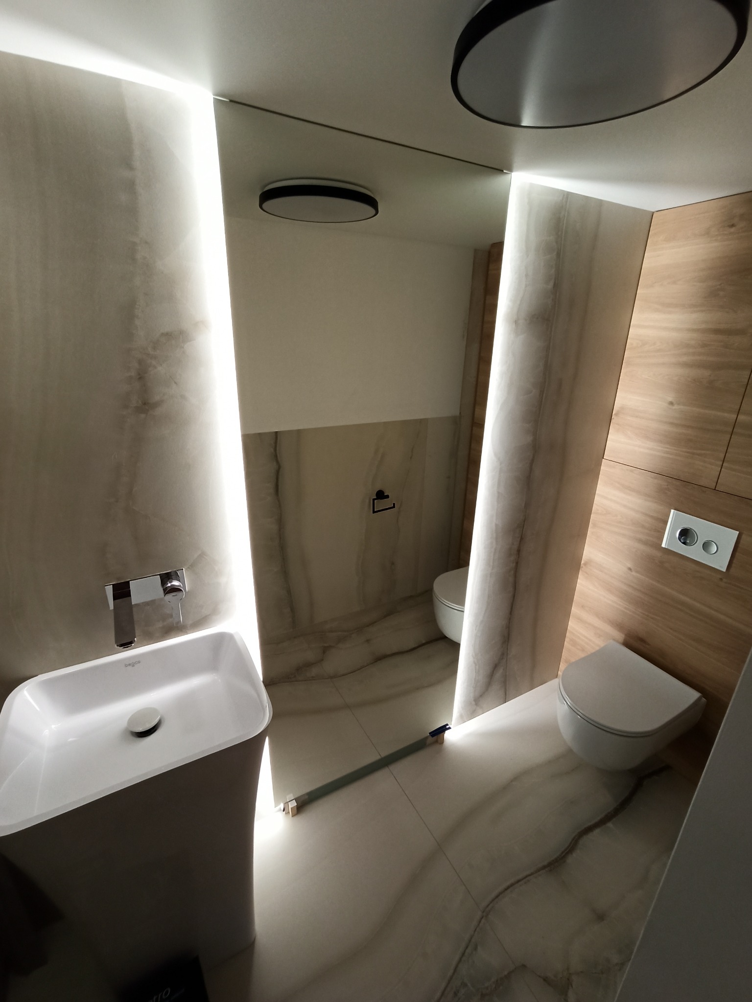 Nowoczesna łazienka z umywalką na postumencie, podświetlanym lustrem i drewnianymi panelami ściennymi, widok z góry.