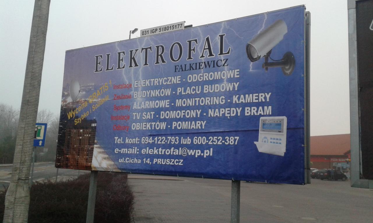 Billboard firmy Elektrofal Falkiewicz z ofertą instalacji elektrycznych, odgromowych, systemów alarmowych, monitoringu i kamer, umieszczony przy drodze w Pruszczu.