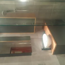 Nowoczesna łazienka z umywalką nablatową wpuszczoną w drewniany blat, szafka pod umywalką w kolorze grafitowym, lustro z podświetleniem LED i prysznicem typu walk-in z grafitowymi płytkami.