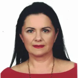 Portret kobiety z ciemnymi włosami, ubranej w czerwoną bluzkę i czarny naszyjnik, na białym tle.