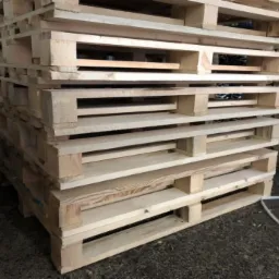 Stos jasnych, surowych palet drewnianych ułożonych jedna na drugiej, widoczne sęki i naturalny rysunek drewna, z białym sznurkiem zabezpieczającym na dole.