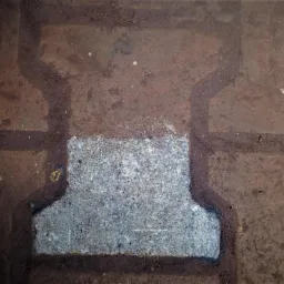 Fragment kostki brukowej po częściowym wyczyszczeniu, widoczne ślady brudu i wody w fugach.