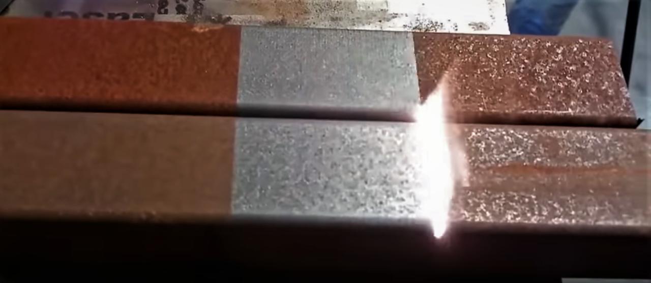 Metalowe profile w trakcie czyszczenia strumieniem ognia, widoczne fragmenty rdzy i ślady po wcześniejszym czyszczeniu.