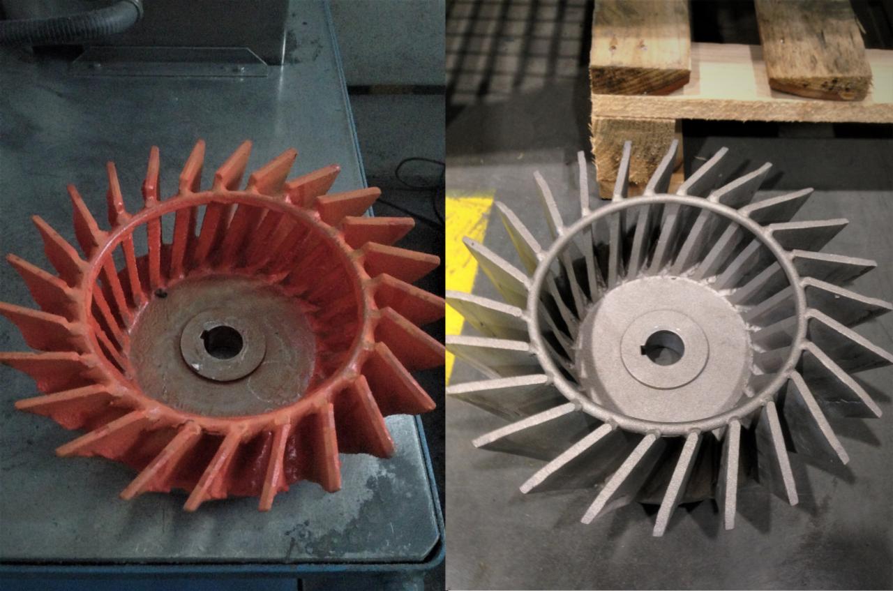 Porównanie dwóch metalowych wirników wentylatorów, jeden pomalowany na pomarańczowo po lewej stronie, drugi surowy, srebrny po prawej stronie, leżący na palecie.