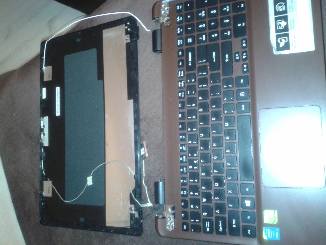 Laptop Acer z odłączoną klapą matrycy, widoczne uszkodzone zawiasy i elementy wewnętrzne obudowy. Klapa leży obok klawiatury, widoczne przewody i taśmy.