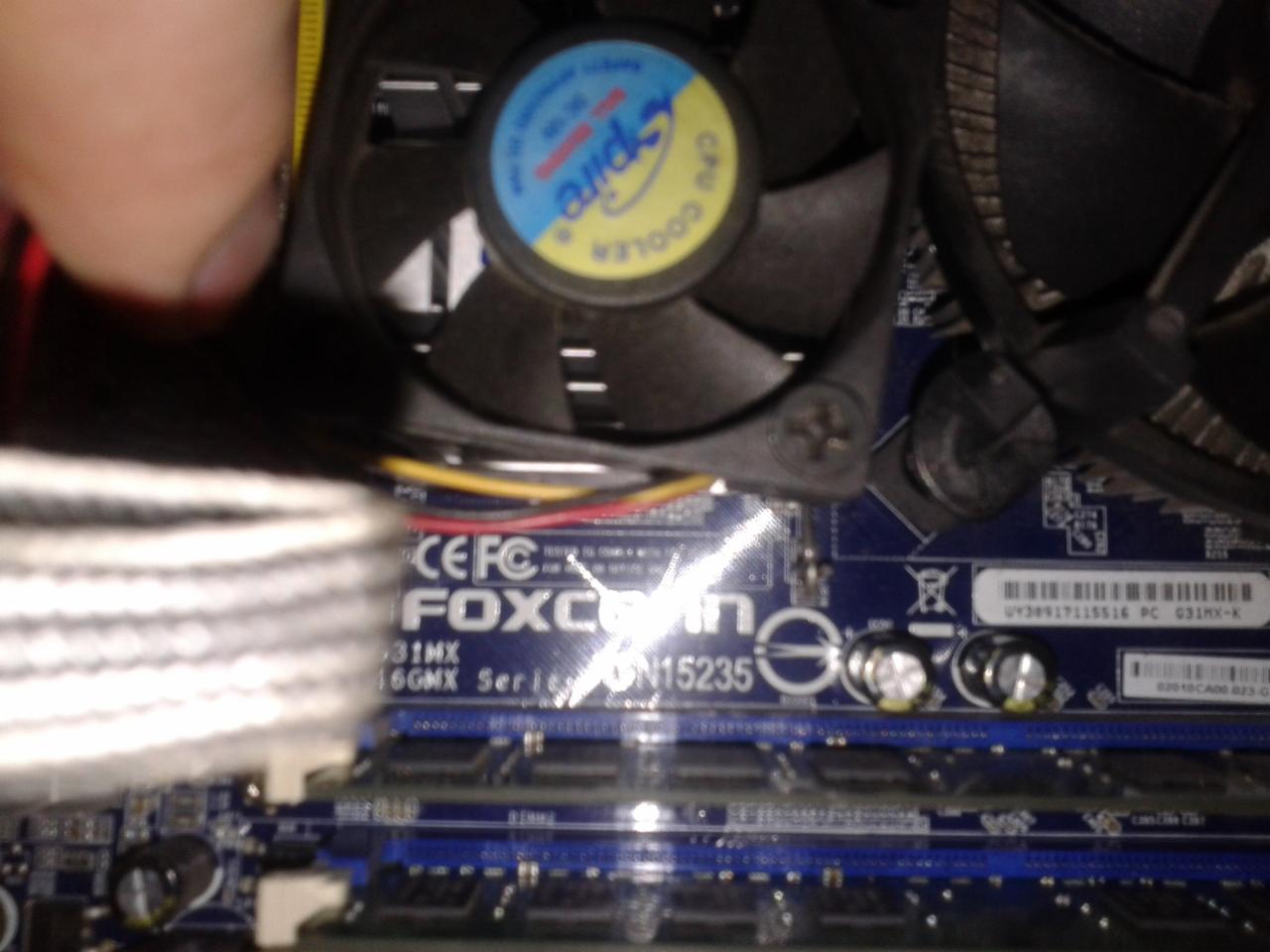 Wymiana chłodzenia procesora na płycie głównej Foxconn G31MX, widoczne kości pamięci RAM i wentylator CPU Cooler z niebiesko-żółtym logo 'pire CPU 1000'.