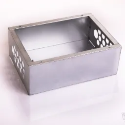 Prostokątna, metalowa obudowa z otworami wentylacyjnymi, wykonana z blachy, z widocznymi śrubami mocującymi narożniki, leżąca na białym tle z odbiciem.