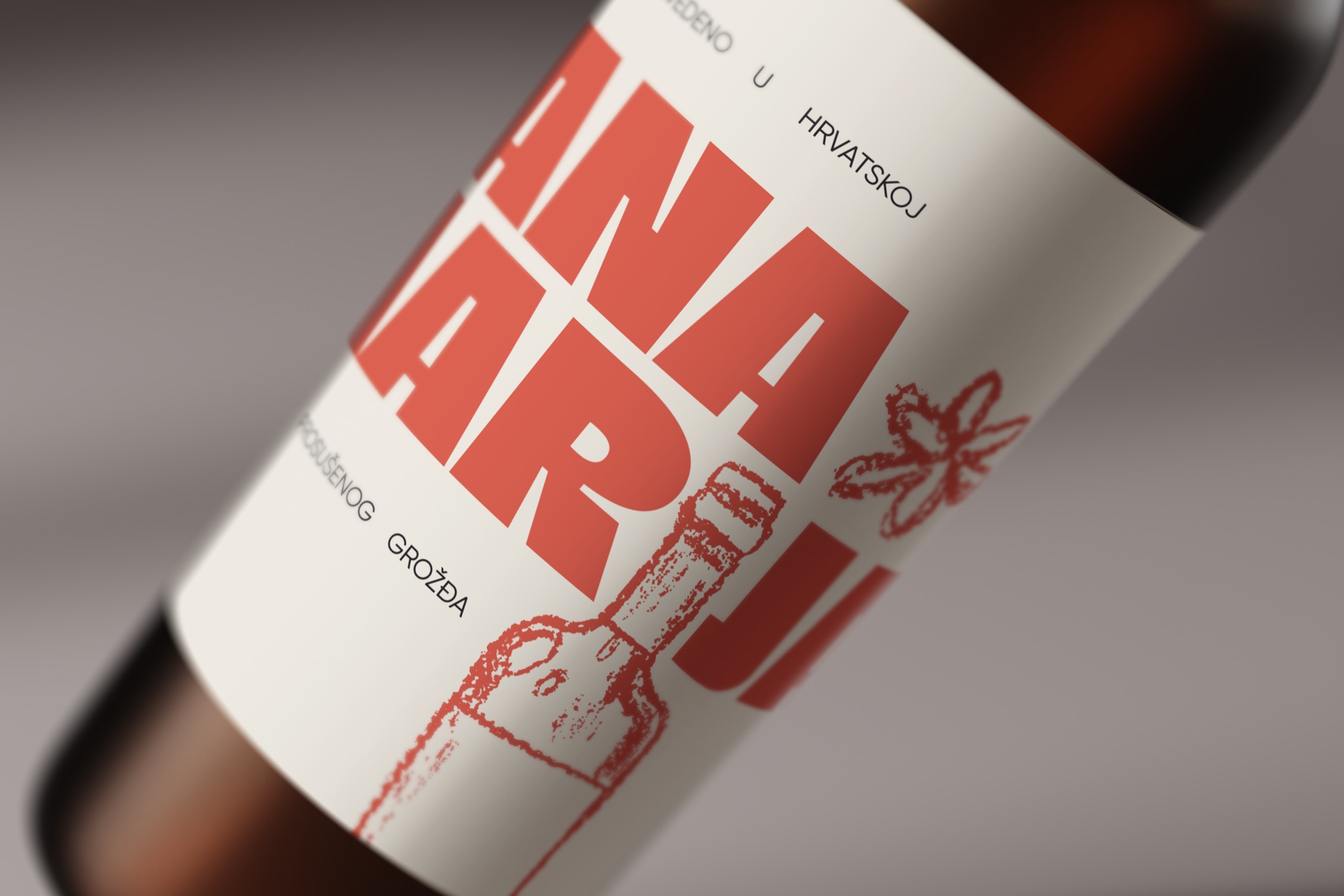 Etykieta butelki wina z dużym czerwonym napisem 'ANA MARIJA' i rysunkami wykonanymi w stylu kredki, umieszczona pod kątem na szarym tle.