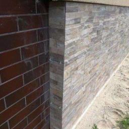 Bud-Ma - Wykończenie cokołu budynku płytkami imitującymi kamień, widoczny fragment ściany z cegły klinkierowej i styk z elewacją.