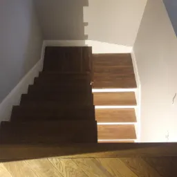 Drewniane schody z podświetleniem LED, widok z góry, parkiet u dołu kadru.