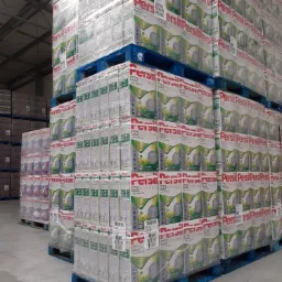 Palety z zapasem profesjonalnego środka czystości Persil Universal, składowane w magazynie z widocznymi stalowymi elementami konstrukcyjnymi.