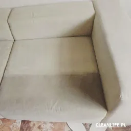 Fragment beżowej kanapy z widoczną różnicą w czystości po zabiegu czyszczenia tapicerki, z wyraźnym odcięciem między wyczyszczoną a nieczyszczoną częścią.