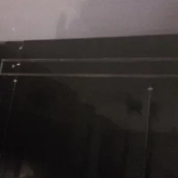 Ciemne, błyszczące płytki w łazience z zamontowanym odpływem liniowym, widoczne krzyżyki dystansowe.