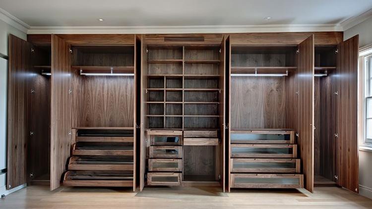 Wnętrze szafy wnękowej z drewna orzechowego, z wysuwanymi półkami na buty, szufladami z przeszklonymi frontami i oświetleniem LED.