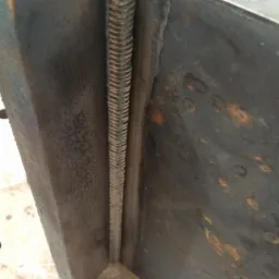 Spoina pachwinowa łącząca dwie stalowe płyty pod kątem prostym, widoczne ślady rdzy na powierzchni metalu.