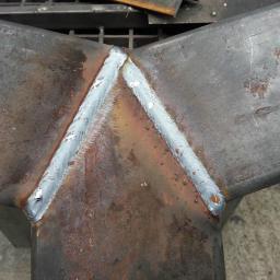 metal - Metalowa konstrukcja spawana w kształcie litery Y, widoczne ślady po spawaniu i niedoskonałości powierzchni metalu.