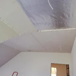Montaż sufitu z płyty karton gips z widoczną izolacją termiczną i fragmentem skośnego poddasza, przygotowany do dalszego wykończenia.