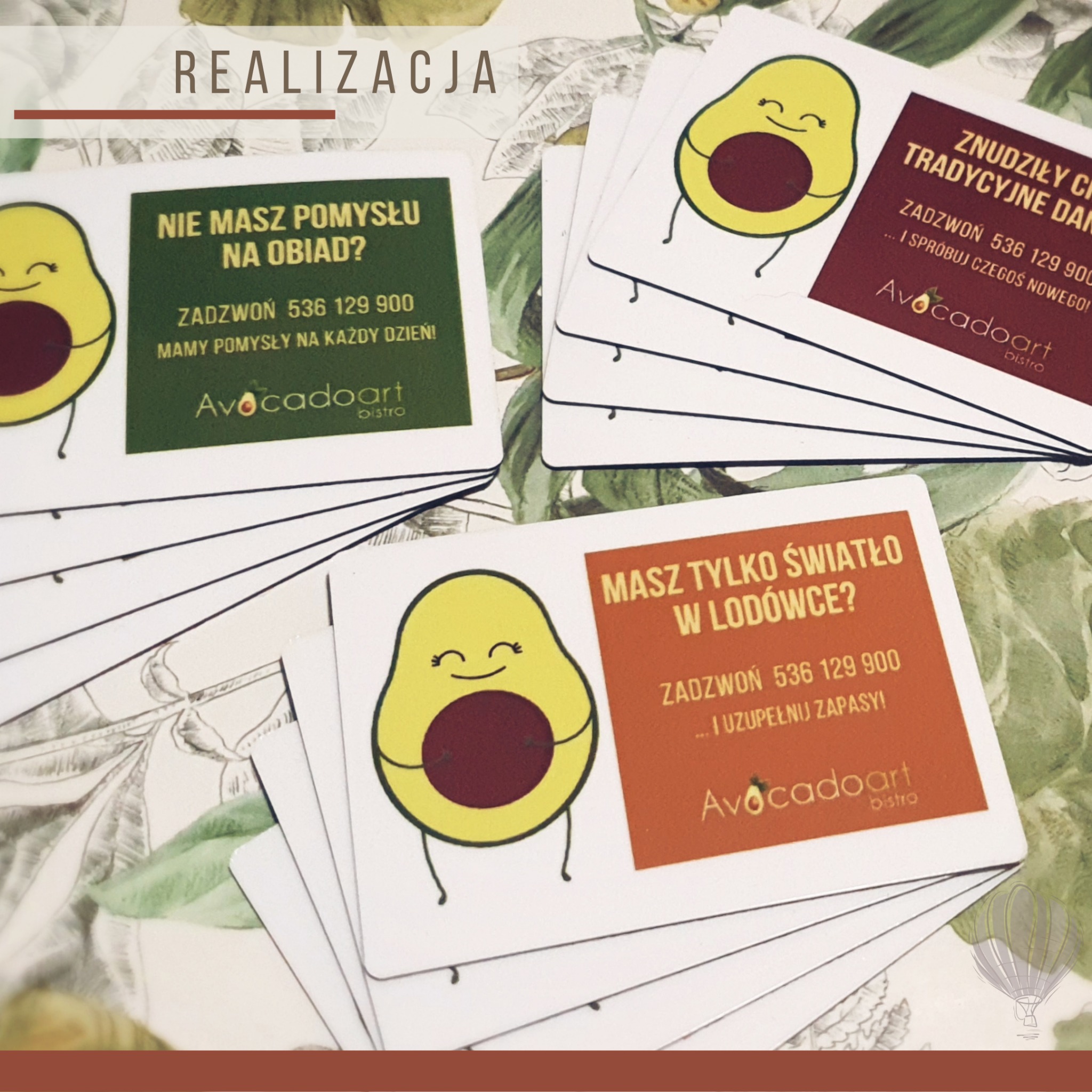 Stos kart z ilustracjami awokado i hasłami reklamowymi restauracji, leżący na tle z motywem roślinnym.