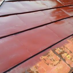 Wash-King Malowanie dachów Łukasz Biernat - Malowanie dachu z blachy na kolor ceglasty z użyciem pistoletu natryskowego. Część dachu pomalowana, widoczne fragmenty z rdzawym nalotem.