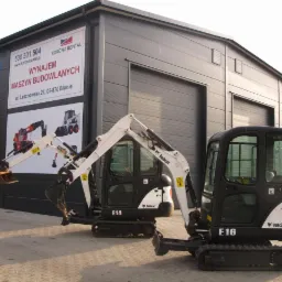 Dwie mini koparki Bobcat E14 i E16 stoją przed budynkiem z napisem 'Wynajem Maszyn Budowlanych' i numerem telefonu.