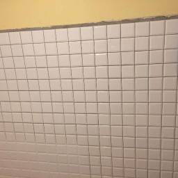 CLEAN MASTER BY TRUST TREE - Ściana wyłożona białymi, kwadratowymi płytkami z ciemnymi fugami, widoczne niedociągnięcia przy suficie i fragment niebieskiej szmatki w prawym górnym rogu.