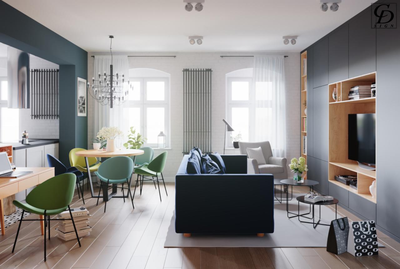 Jasne, przestronne wnętrze mieszkania w Tarnowskich Górach z otwartą kuchnią, okrągłym stołem z kolorowymi krzesłami, granatową sofą i zabudową meblową z telewizorem.