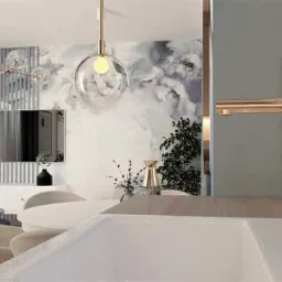 Nowoczesne wnętrze mieszkania z elementami dekoracyjnymi: złota bateria umywalkowa, lampy wiszące z przezroczystymi kloszami, ściana z motywem kwiatowym i logo projektanta w rogu.