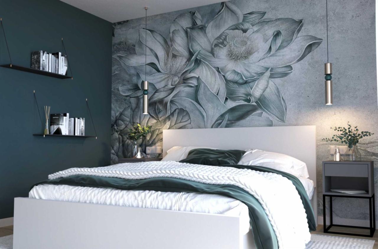 Nowoczesna sypialnia z białym łóżkiem, ciemnozielonymi akcentami i fototapetą z motywem kwiatowym, oświetlona wiszącymi lampami i z półkami na książki na ścianie.