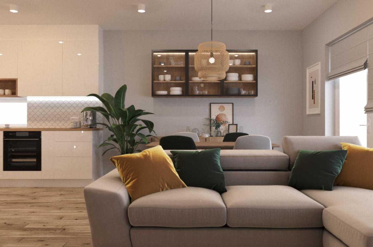 Jasne, przestronne wnętrze z kuchnią w tle, widok na salon z beżową sofą z żółtymi i zielonymi poduszkami, drewniany stół z krzesłami, przeszklona szafka na ścianie i wisząca lampa z abażurem...