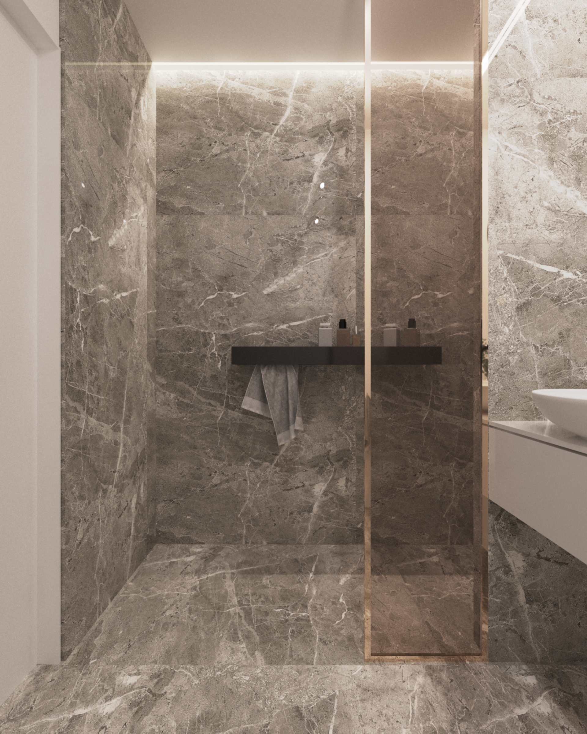 Nowoczesna łazienka z marmurowymi ścianami i podłogą, szklana kabina prysznicowa z złotymi ramami, minimalistyczna czarna półka z kosmetykami i wiszący szary ręcznik.