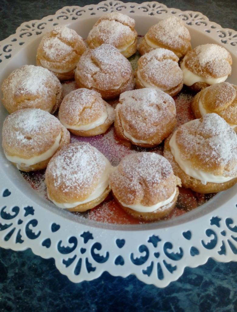 Patera z ptysiami wypełnionymi kremem i posypanymi cukrem pudrem, przygotowanymi przez cukiernię z Grajewa.