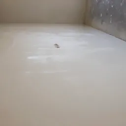 Wyrównana, jasna podłoga po wylaniu samopoziomu, widoczne ślady po wałku odpowietrzającym i wystające puszki elektryczne w nowym pomieszczeniu.