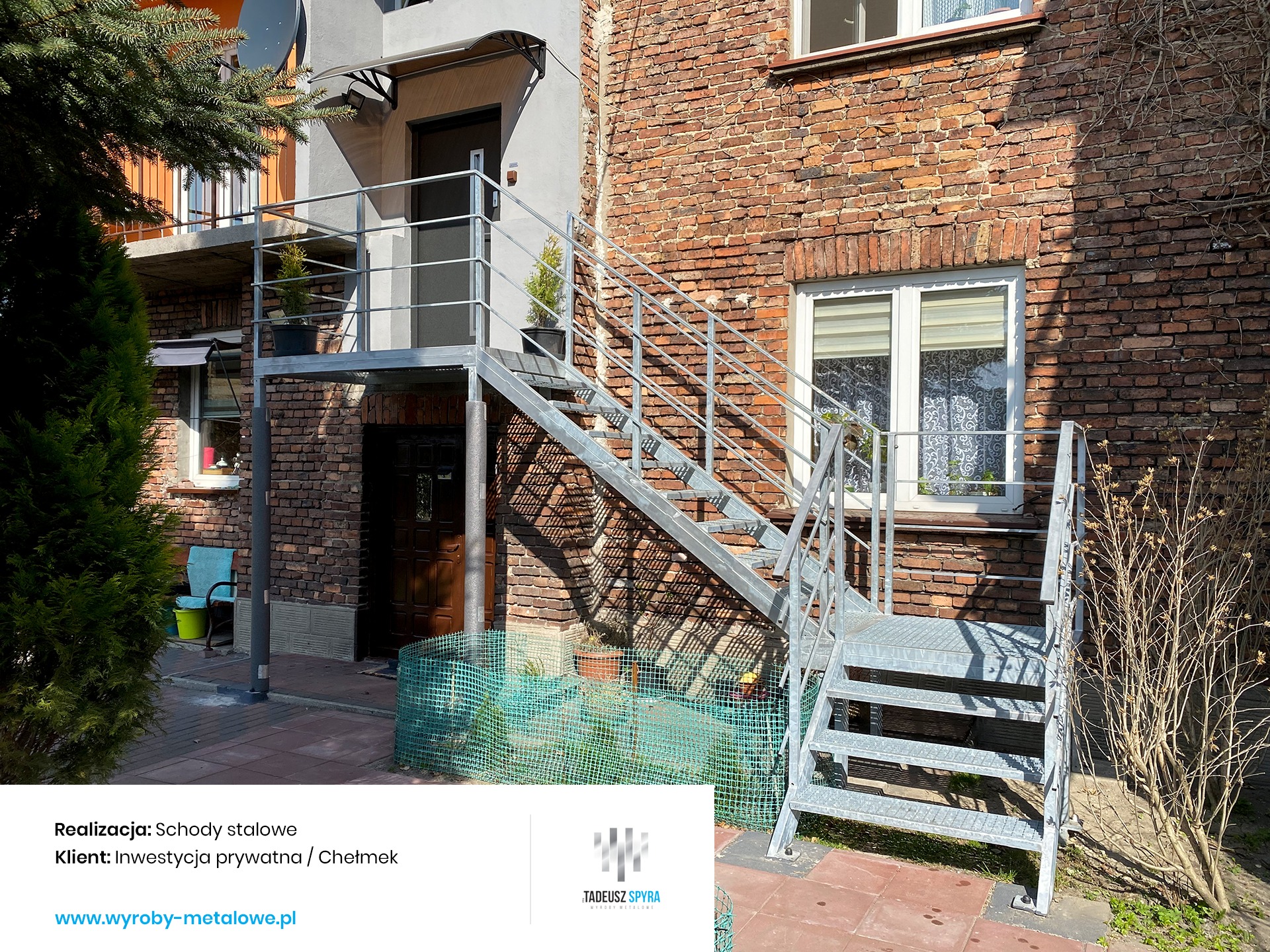 Zewnętrzne, ocynkowane schody z metalu prowadzące na balkon, przylegające do ceglanego budynku z oknami.