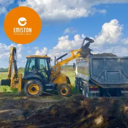 Żółta koparko-ładowarka JCB załadowuje ziemię do skrzyni wywrotki na tle zielonego pola i błękitnego nieba z chmurami. W lewym górnym rogu widoczne logo firmy Emiston.