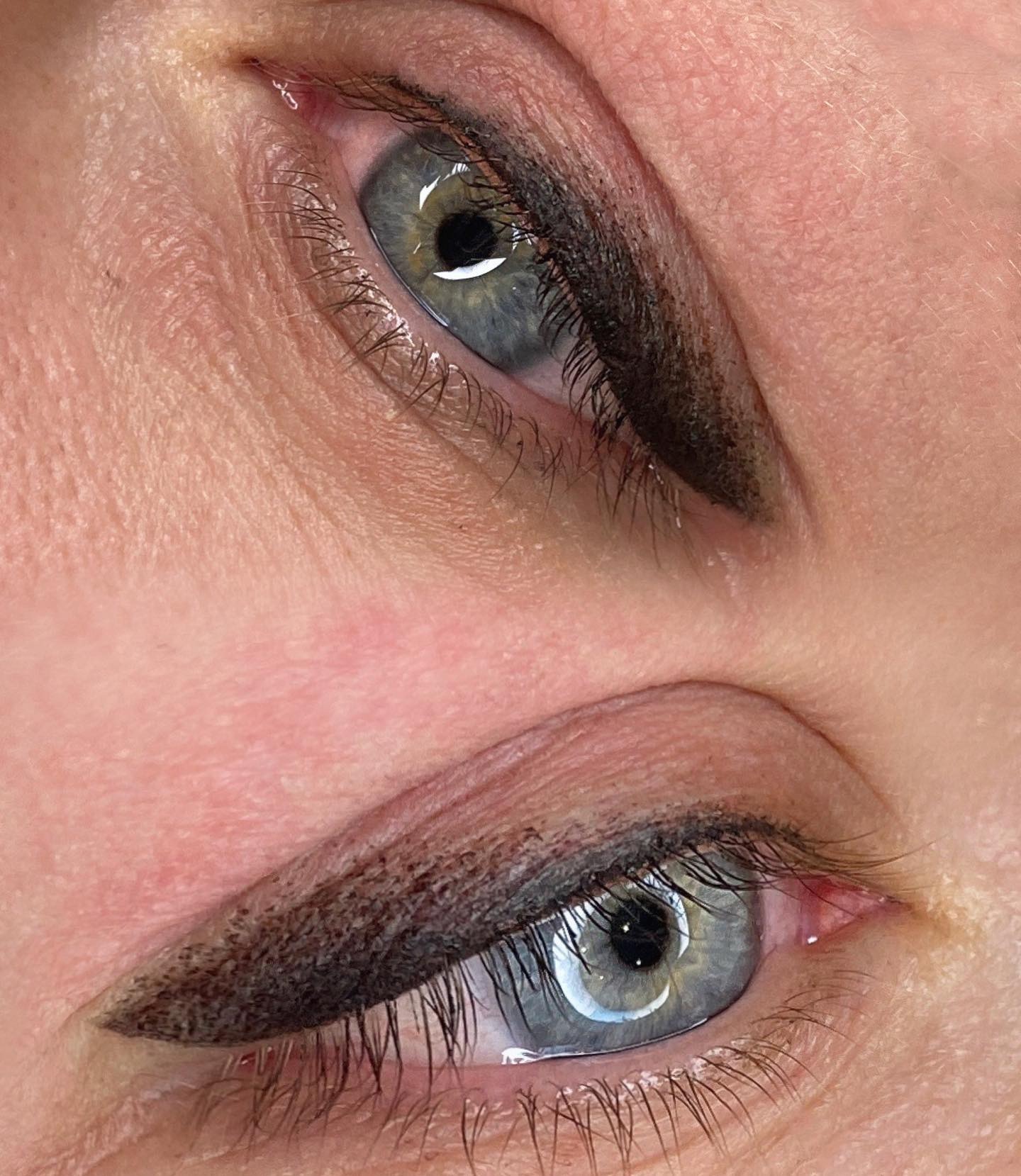 Zbliżenie na dwa oczy z wykonanym makijażem permanentnym, widoczna precyzyjna kreska na powiece górnej, podkreślająca linię rzęs.